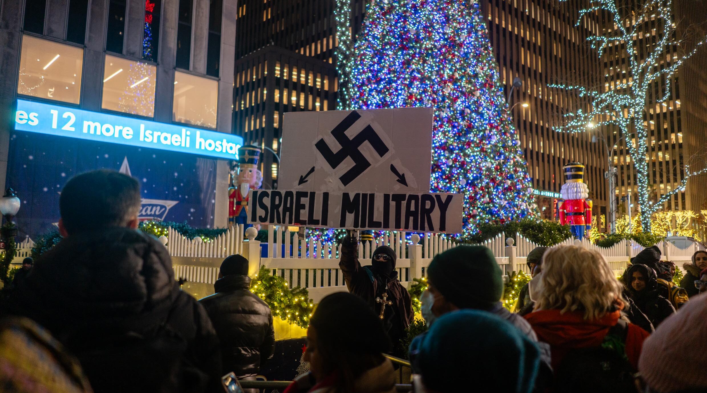 Des manifestants brandissent des croix gammées lors d’un rassemblement pro-palestinien devant l’éclairage du sapin de Noël du Rockefeller Center