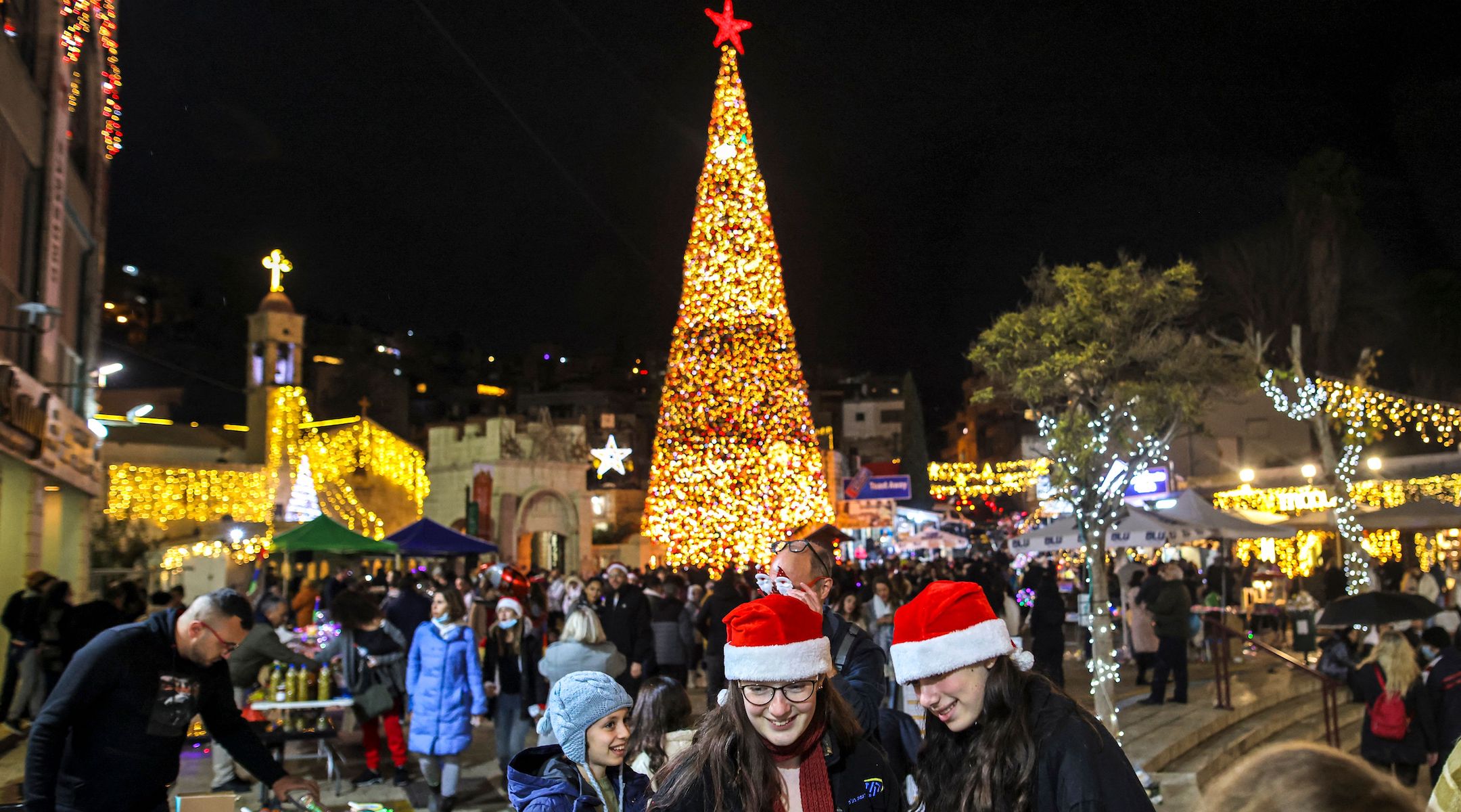 Des gens se rassemblent devant le sapin de Noël de Nazareth avant les vacances de 2021. (Ahmad Gharabli/AFP via Getty Images)