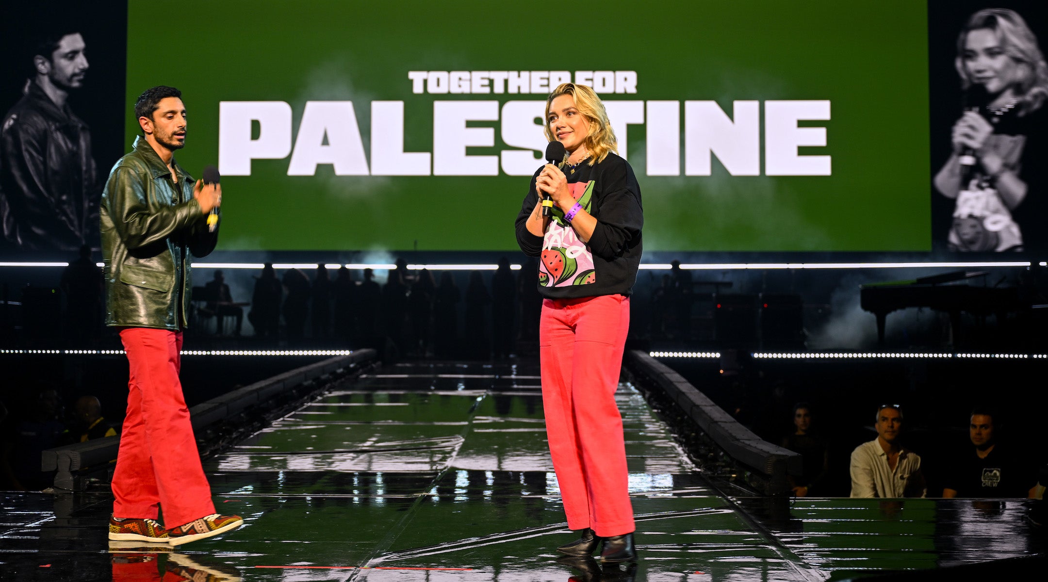 Riz Ahmed and Florence Pugh, wearing a watermelon sweatshirt, onstage at a pro-Palestinian fundraiser concert