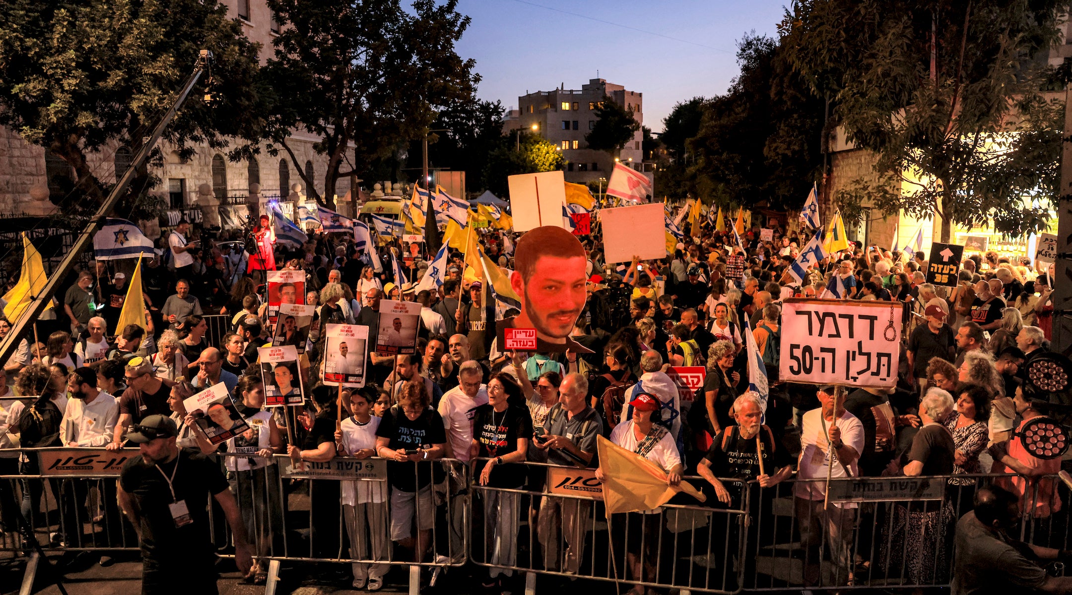 A photo of protesters for the release of the hostages up against a barricade in Israel.