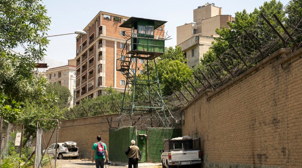 A photo of journalists walking near a watch tower at the prison.
